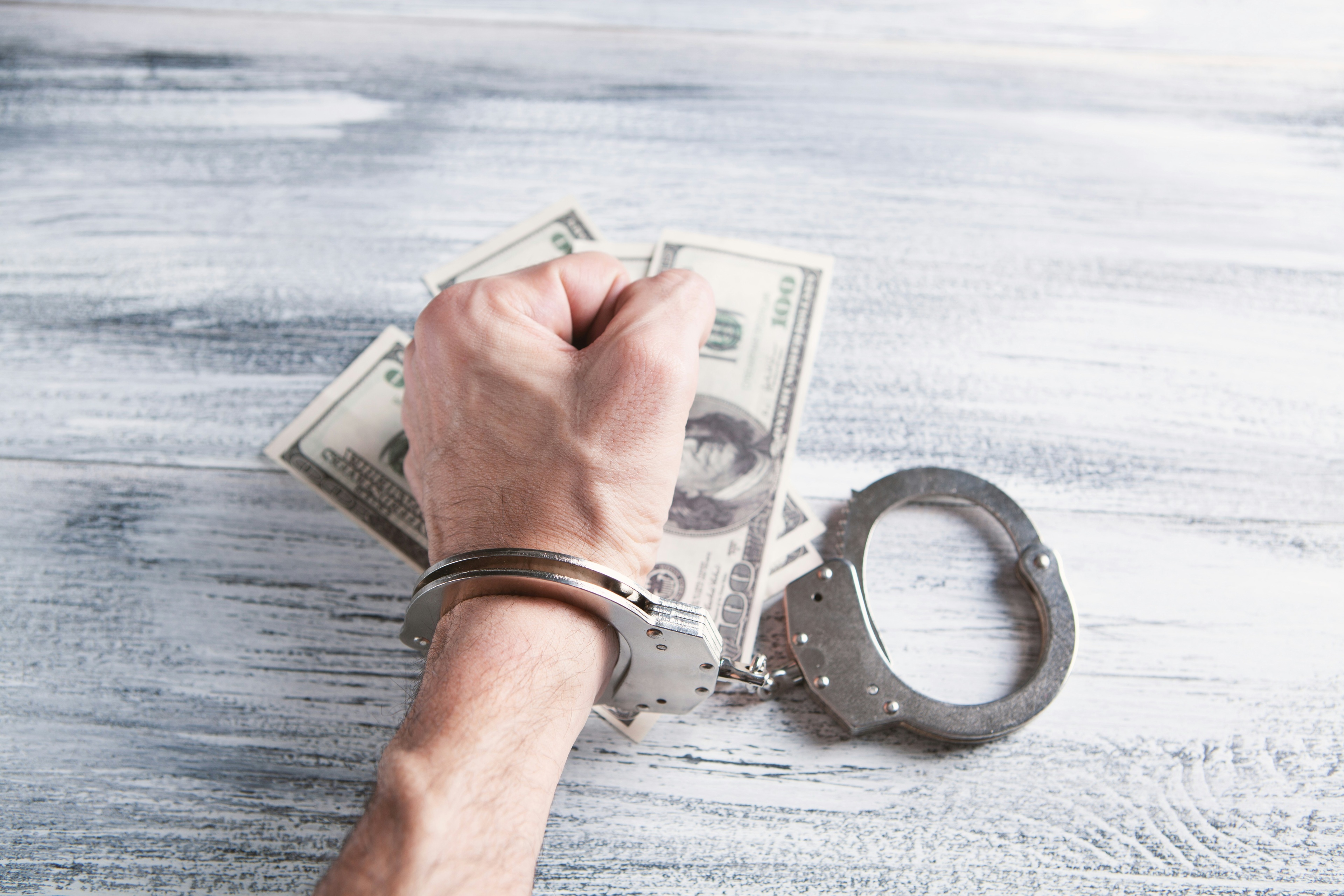A Person In Handcuffs For Money Laundering Charges.