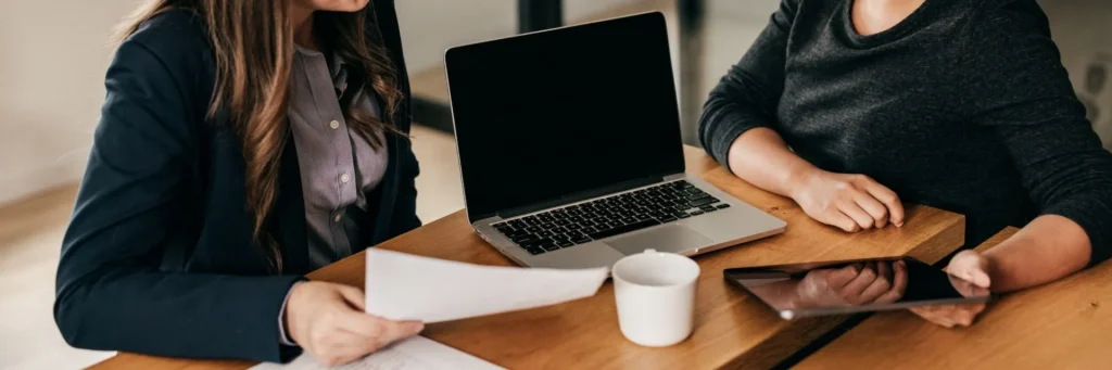 Lawyers Reviewing Financial Documents On A Laptop For A Client Facing Fraud Charges In Qld