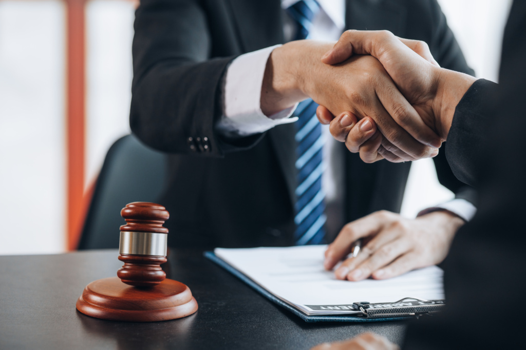 Lawyer shaking hands with a client beside a gavel after advice on fraud charges in QLD
